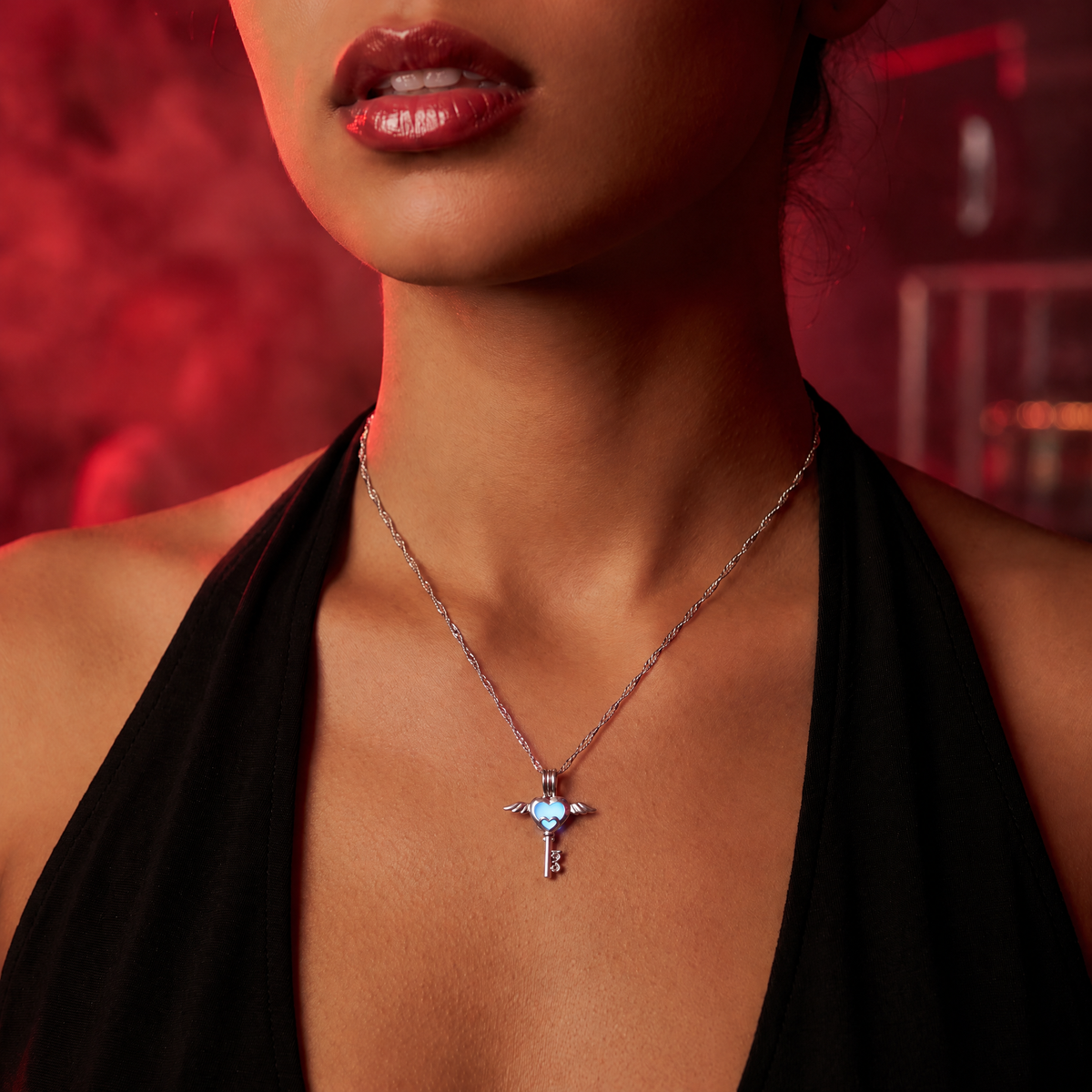 Luminous Love Key Necklace worn at night. Red-lit techno club, editorial crop.