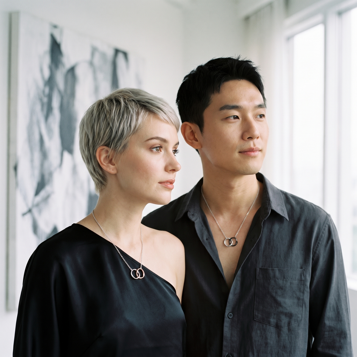 Aureole Mobius Coupled Ring Necklaces worn by a couple in a contemporary art gallery